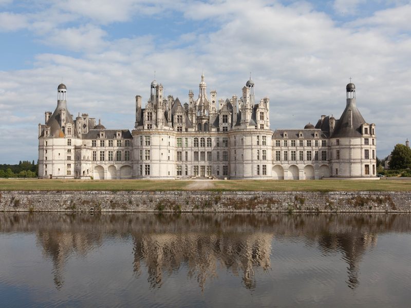 Chateau de Chambord reflected in the water under a blue sky